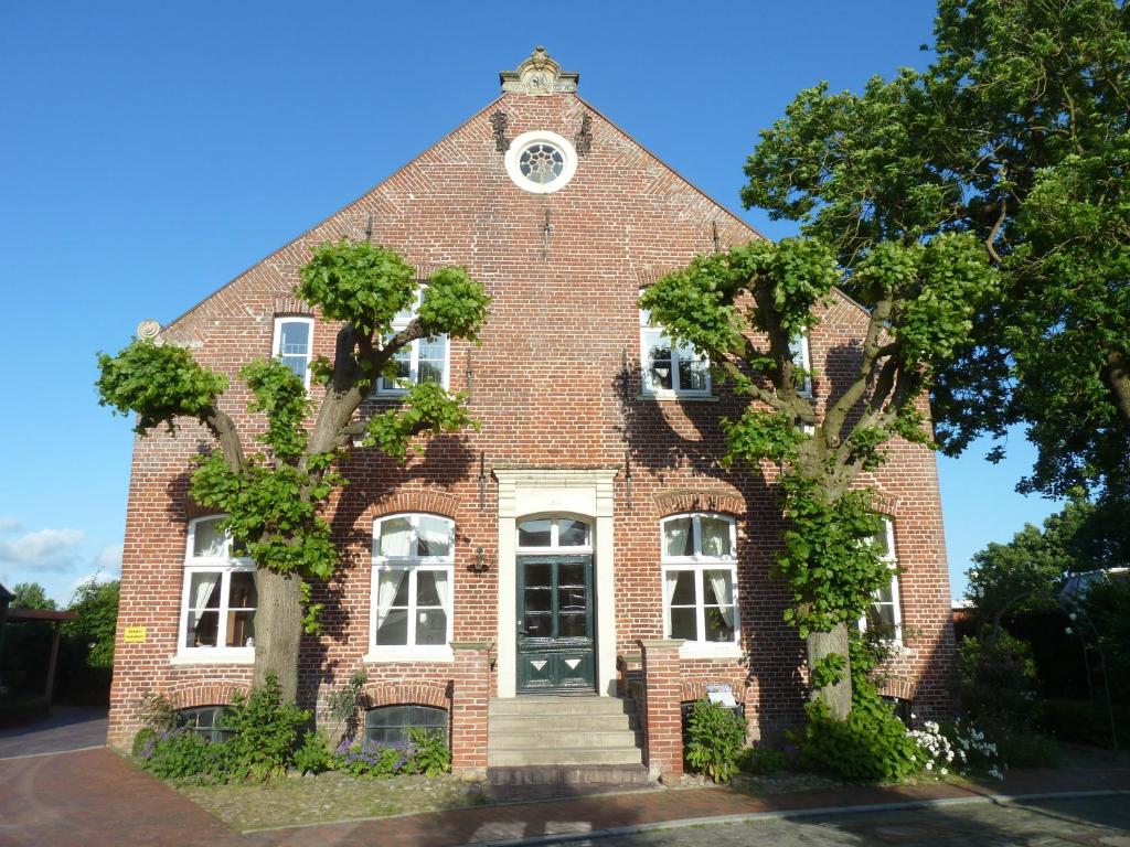 un edificio in mattoni rossi con una torre dell'orologio di Hof Homfeld a Ditzum