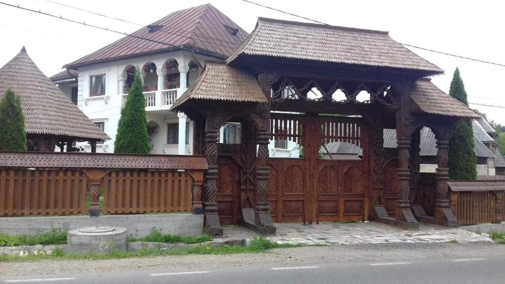 un gran edificio de madera con una puerta frente a una casa en Pensiunea Denisa en Bîrsana