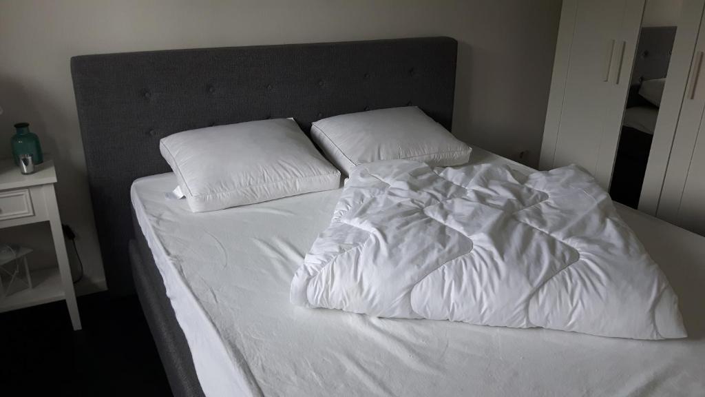 een bed met witte lakens en kussens erop bij Chalet 36 in Giethoorn