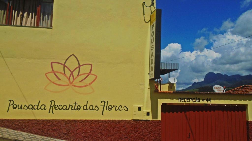 a building with a sign on the side of it at Pousada Recanto das Flores in Aiuruoca