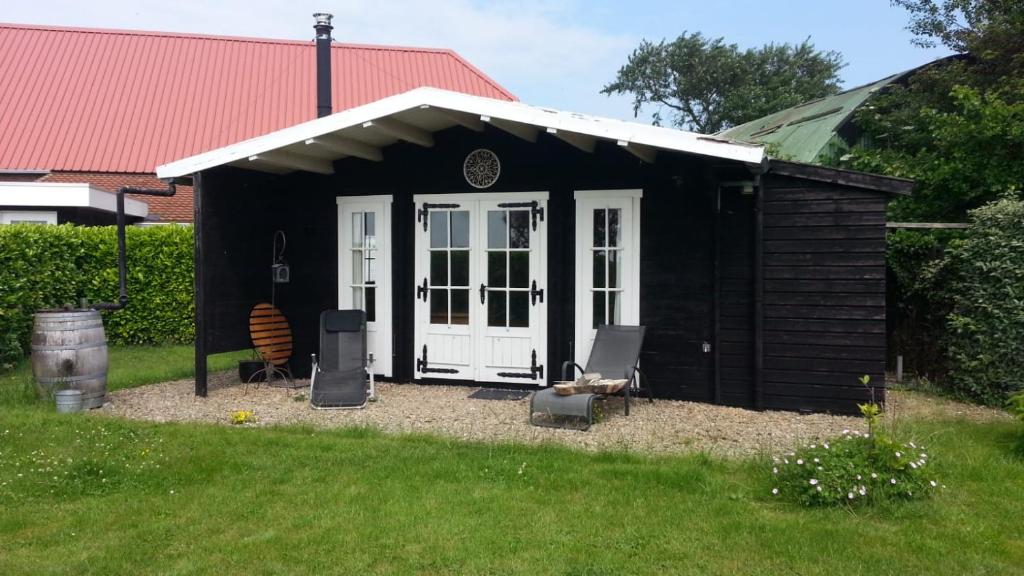 a black shed with a white door in a yard at Koningsheim in Colijnsplaat