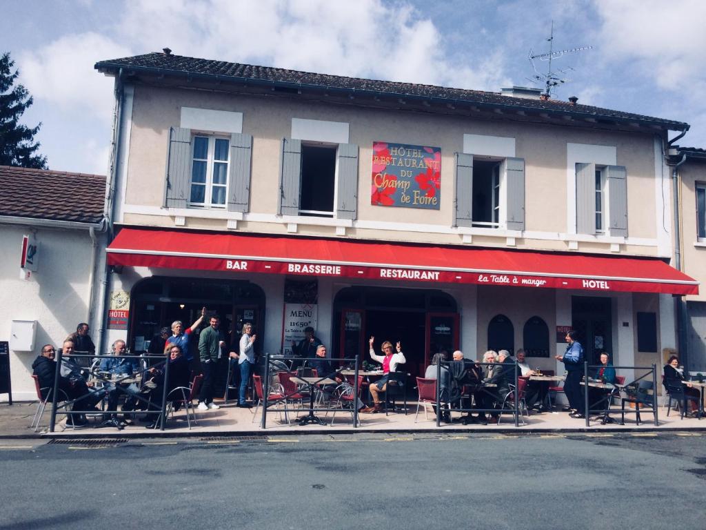 um grupo de pessoas sentadas fora de um edifício em Hotel Du Champ De Foire em Saint-Aulaye