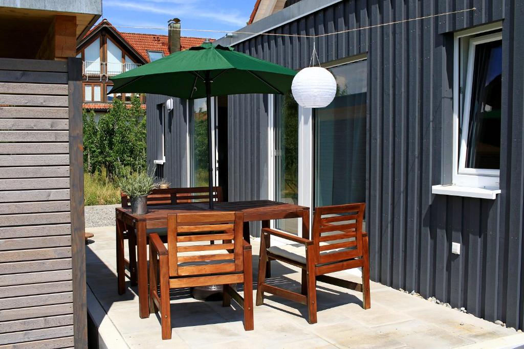 a wooden table with two chairs and a green umbrella at Zum Seglerhafen – Ferienappartement in Kressbronn am Bodensee