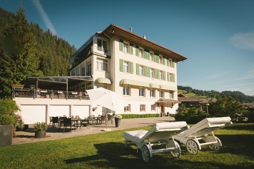 um grande edifício com duas cadeiras de jardim em frente em Sonnegg Hotel em Zweisimmen