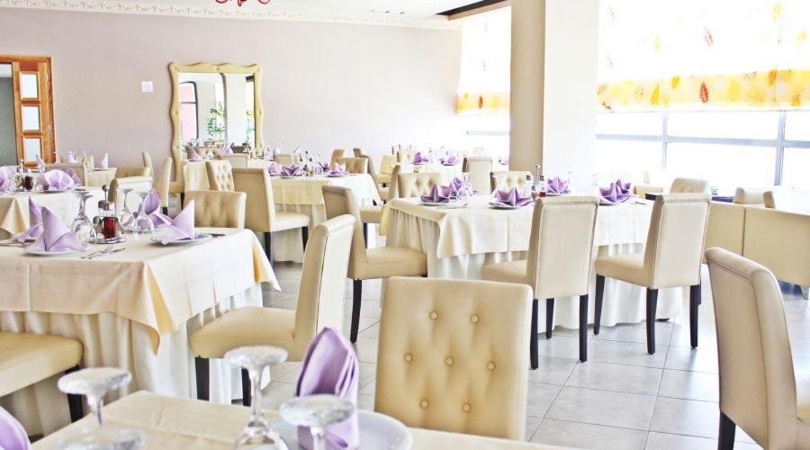 un comedor con mesas y sillas con servilletas púrpuras en Aurelis Hotel, en Bërxull
