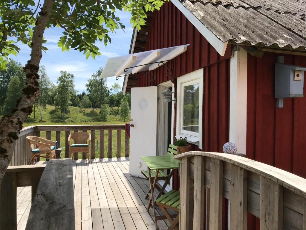 a red house with a wooden deck with a chair at Torpet Längtan in Ullared