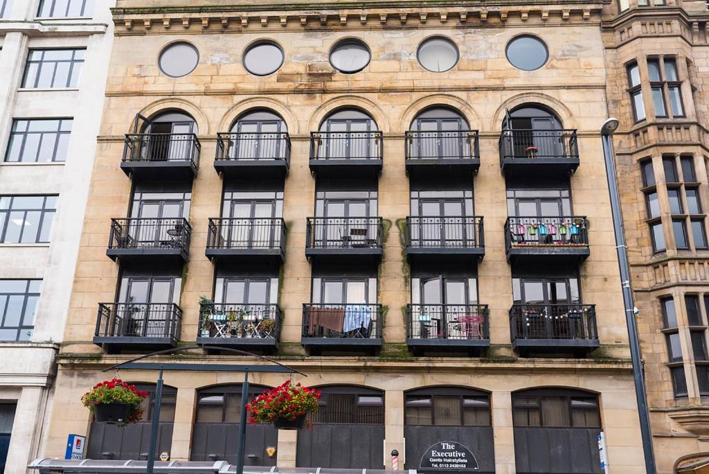 a tall brick building with windows and balconies at Victoria House Apartments in Leeds