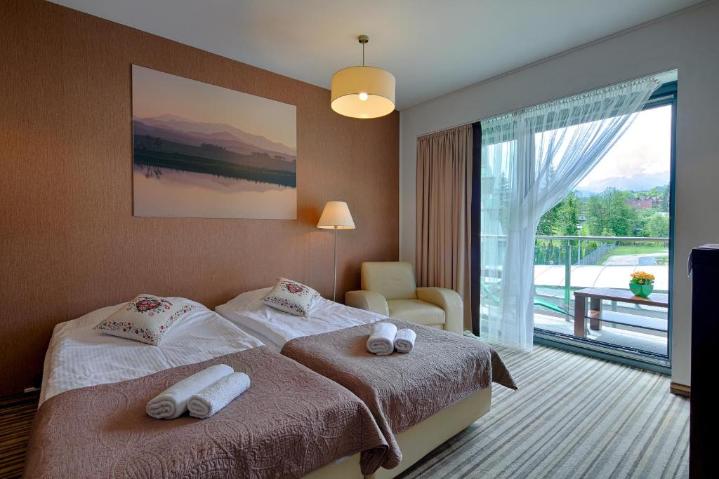 ザコパネにあるApartament Szklane Domyのベッド2台と大きな窓が備わるホテルルームです。