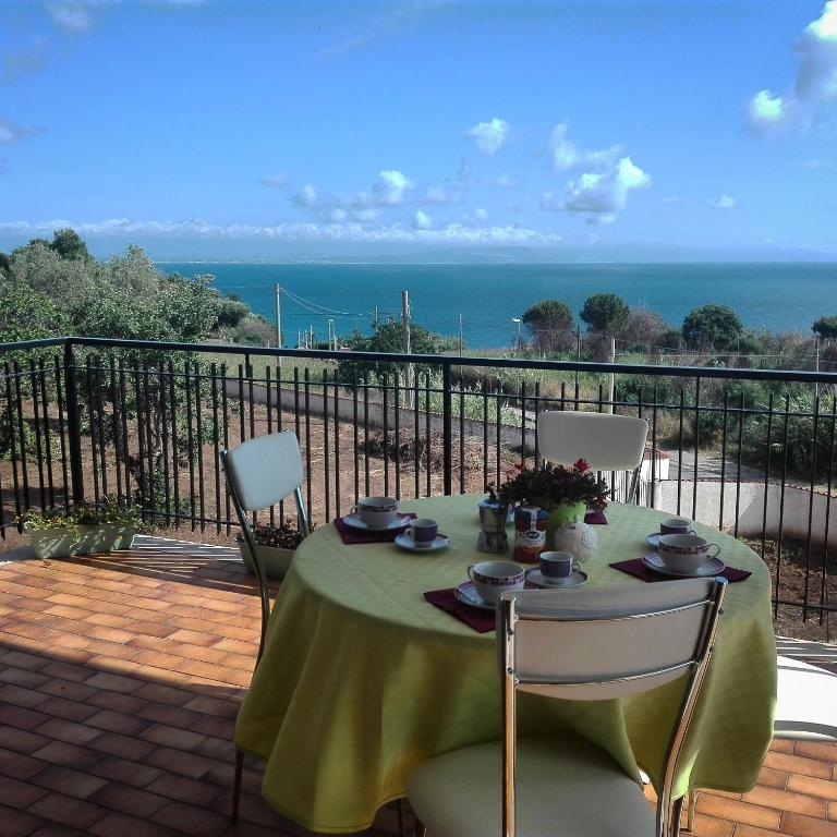 a table with a green table cloth and chairs on a balcony at Michela's house in Capo Vaticano