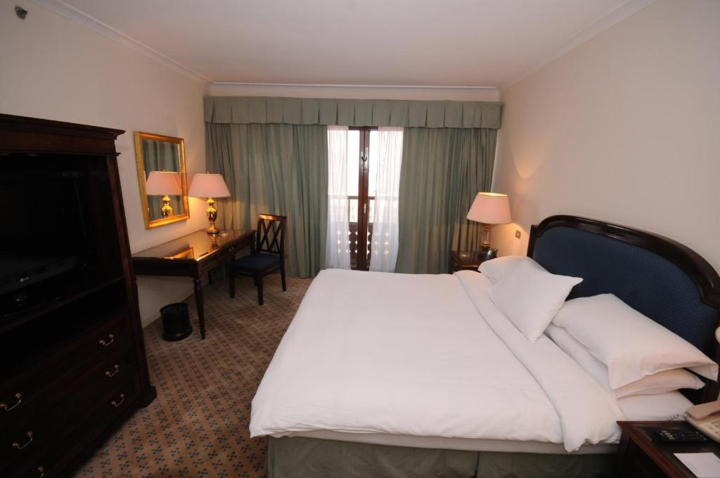 a hotel room with a large bed and a desk at Cairo World Trade Center Hotel & Residences in Cairo