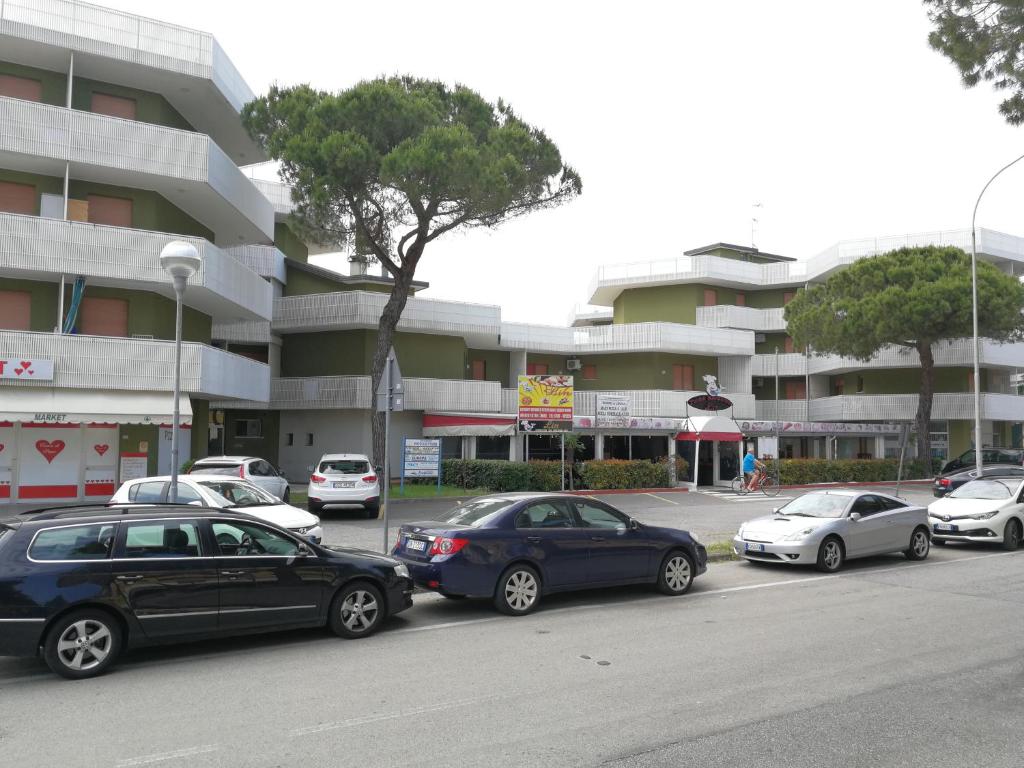 un gruppo di auto parcheggiate di fronte a un edificio di Condominio Moschettieri trilocale a Bibione