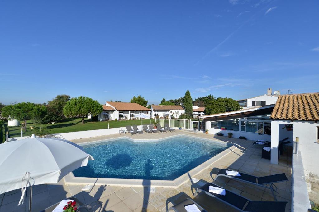 una piscina con sillas y sombrilla en Mas de la Grenouillère Hôtel et Centre équestre en pleine nature, en Saintes-Maries-de-la-Mer