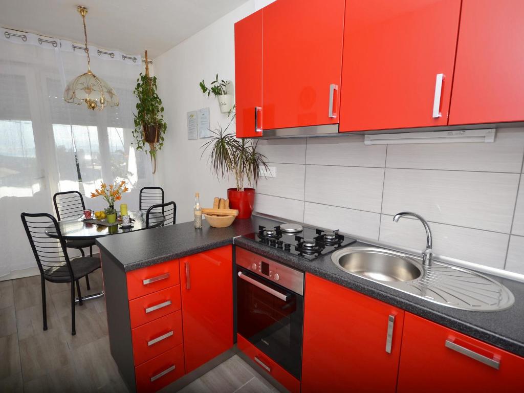 cocina con armarios rojos, fregadero y mesa en Sunshine Apartment, en Split