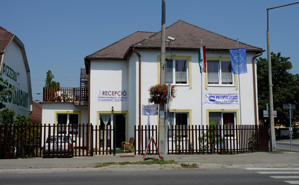 Ein weißes Gebäude mit einem Zaun davor. in der Unterkunft Balaton Vendégház Fonyód in Fonyód