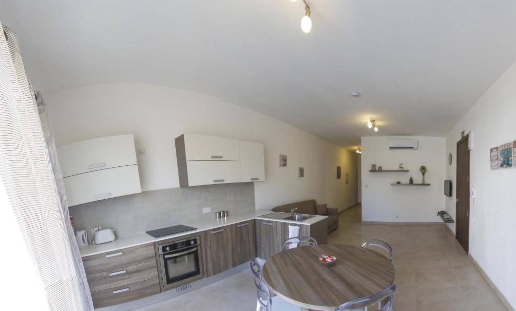 een keuken met witte kasten en een tafel en een kamer bij Pierre & Liana's place in Msida