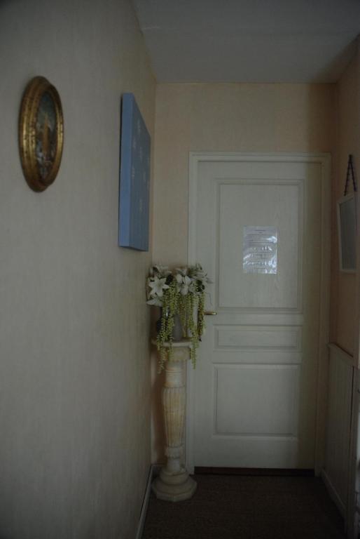 a hallway with a white door and a vase with flowers at Les Fleurs in Monpazier