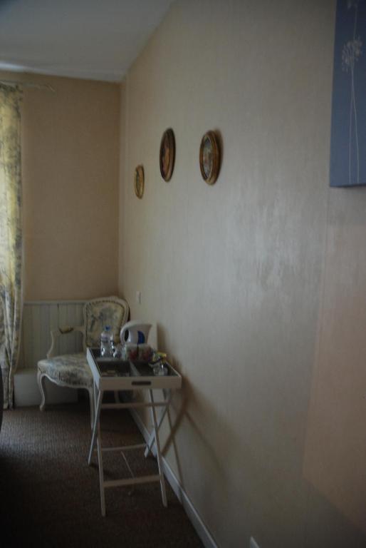 a room with a table and a chair and clocks on the wall at Les Fleurs in Monpazier