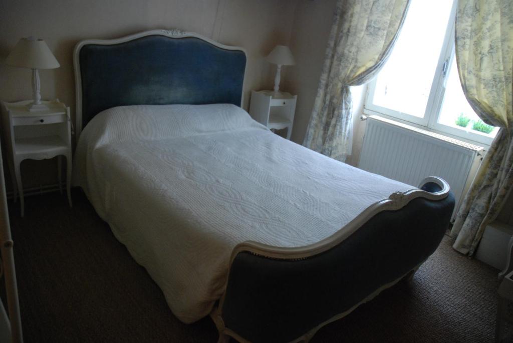 a bedroom with a large bed with a blue headboard and a window at Les Fleurs in Monpazier