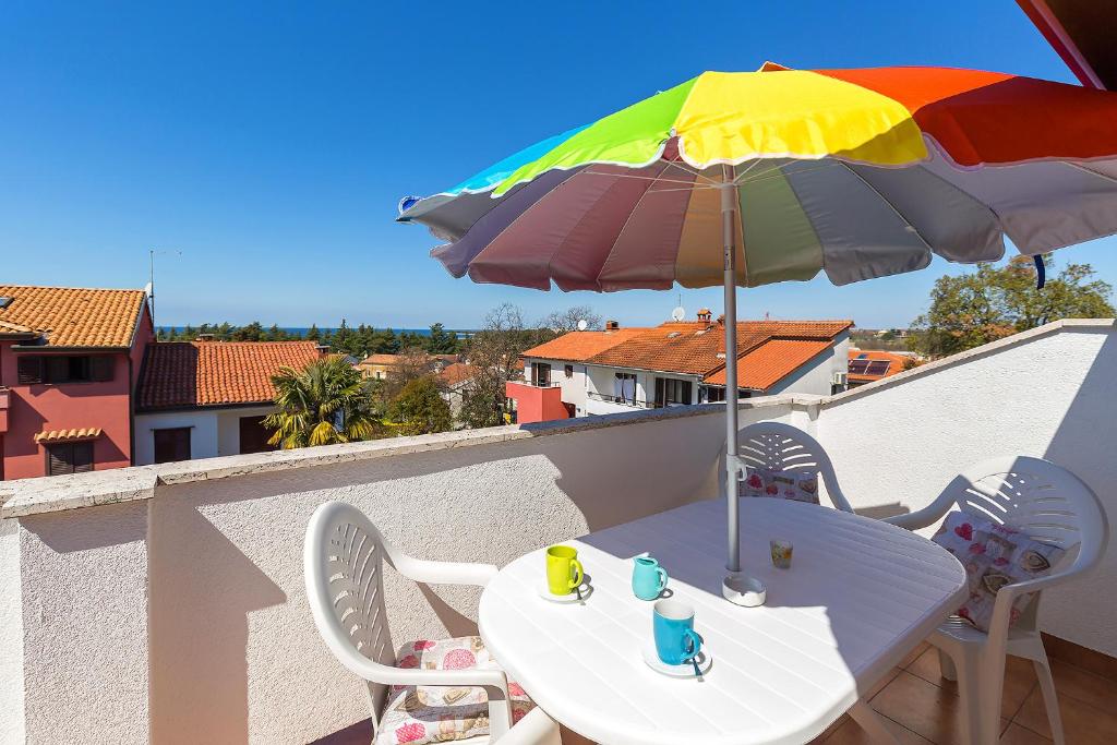- une table avec un parasol coloré sur un balcon dans l&#39;établissement Elena, à Poreč