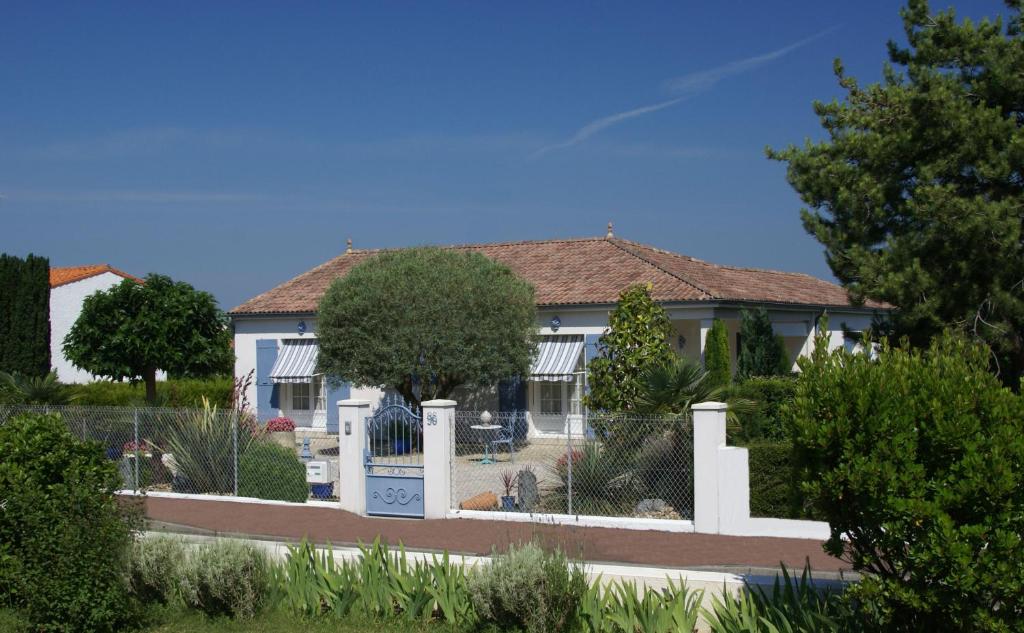 Biały dom z płotem przed nim w obiekcie Appartement de vacances - VILLA L'OLIVIER w mieście Vaux-sur-Mer