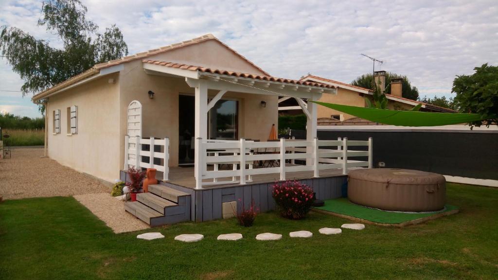 a small house with a white fence in a yard at La Rivière in Pujols Gironde