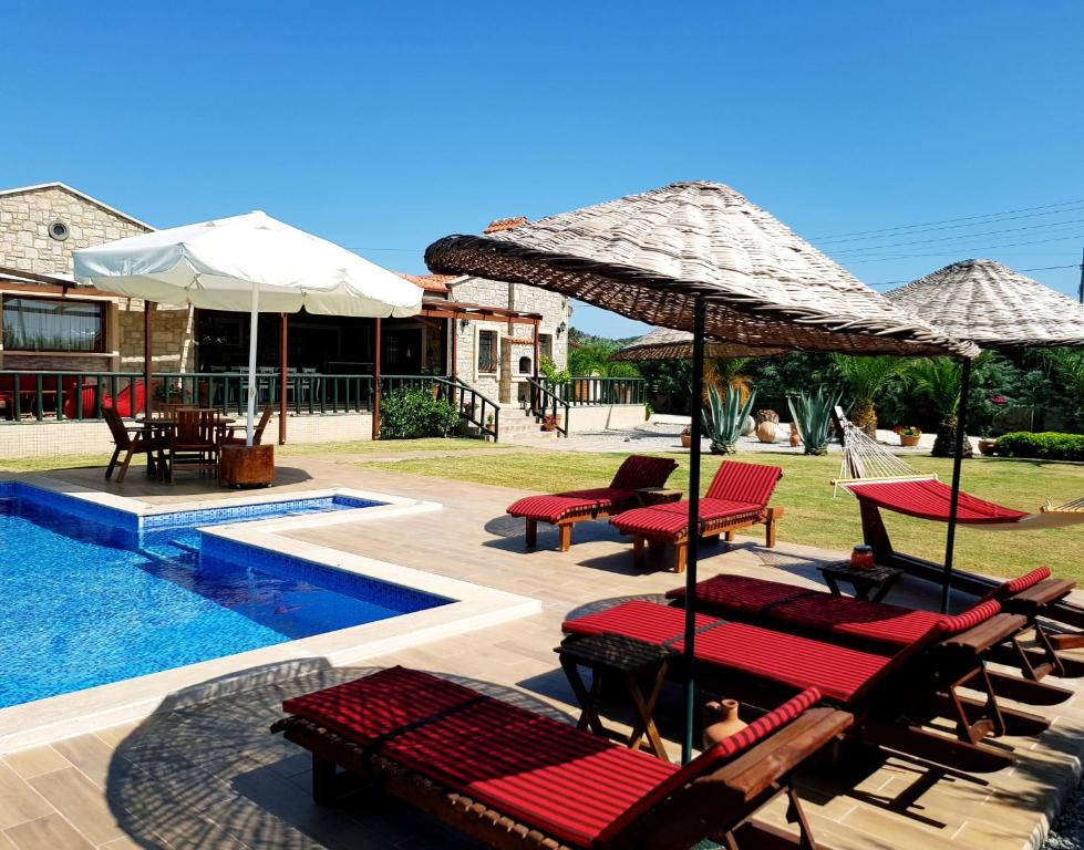 una piscina con sillas y sombrillas junto a un complejo en Villa Kizlan Ova en Datca