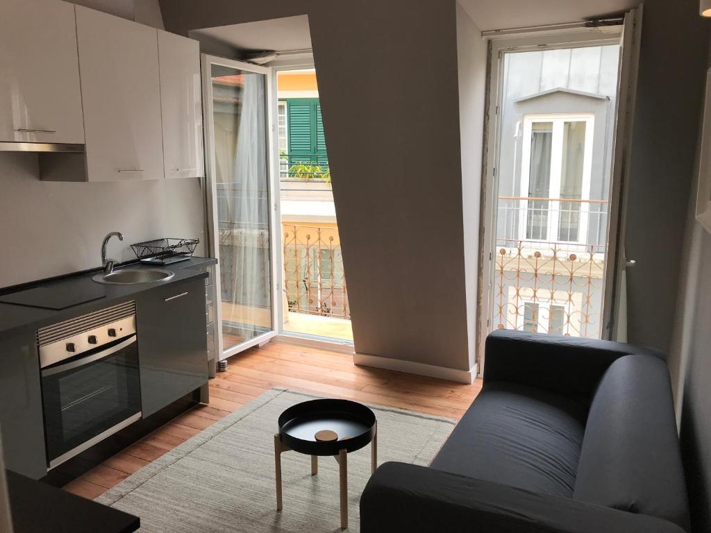 ein Wohnzimmer mit einem Sofa und einer Küche in der Unterkunft The George Flat in Lissabon