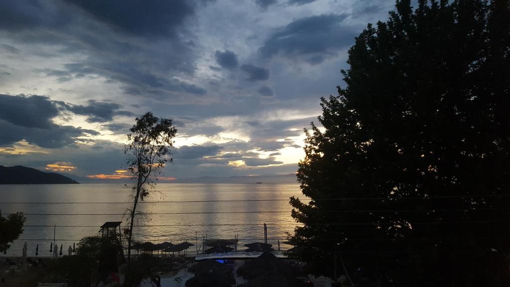 a sunset over a body of water with a tree at Bay View in Limenas
