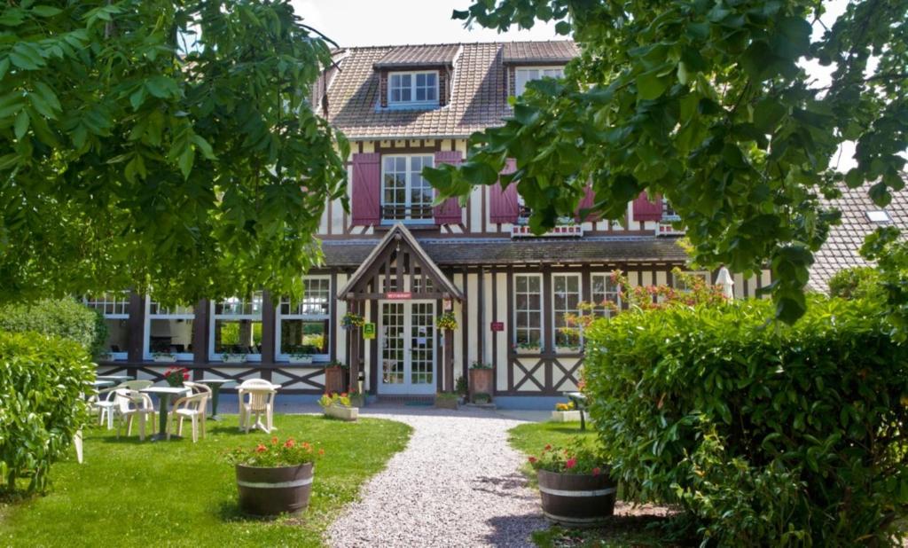 um edifício com um jardim com mesas e cadeiras em Logis Auberge des Aulnettes em Houlgate