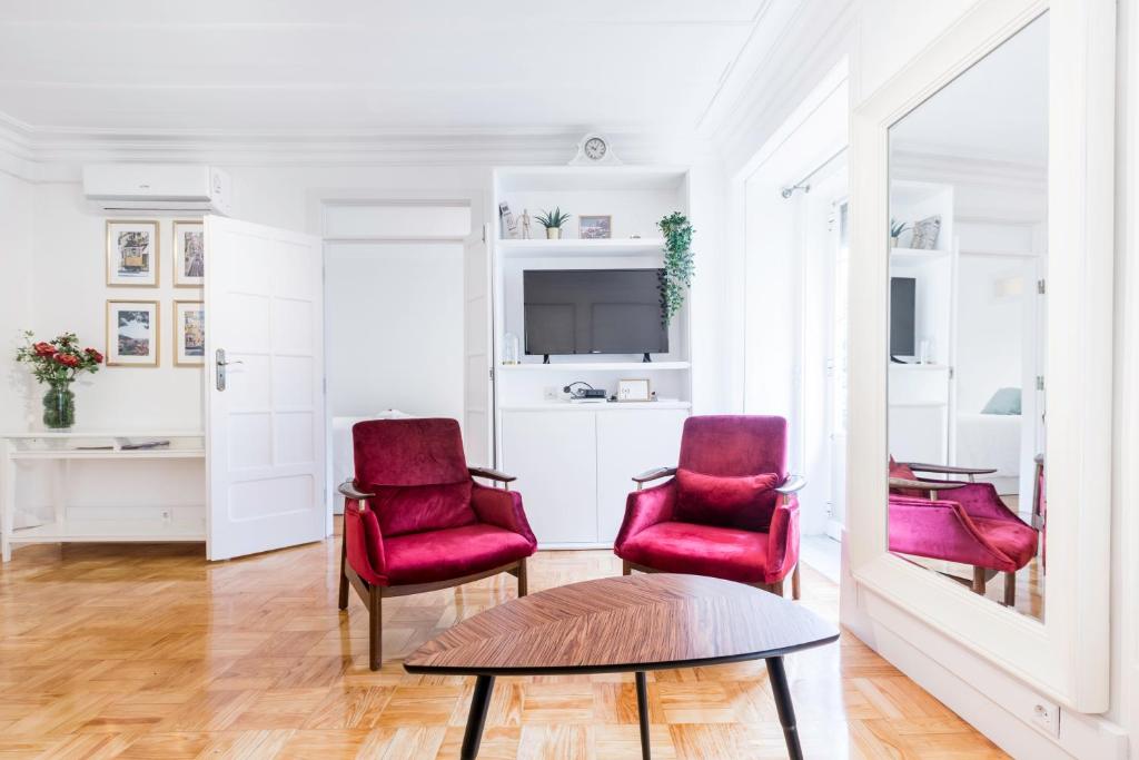 een woonkamer met 2 rode stoelen en een tafel bij Your Place in Lisbon in Lissabon