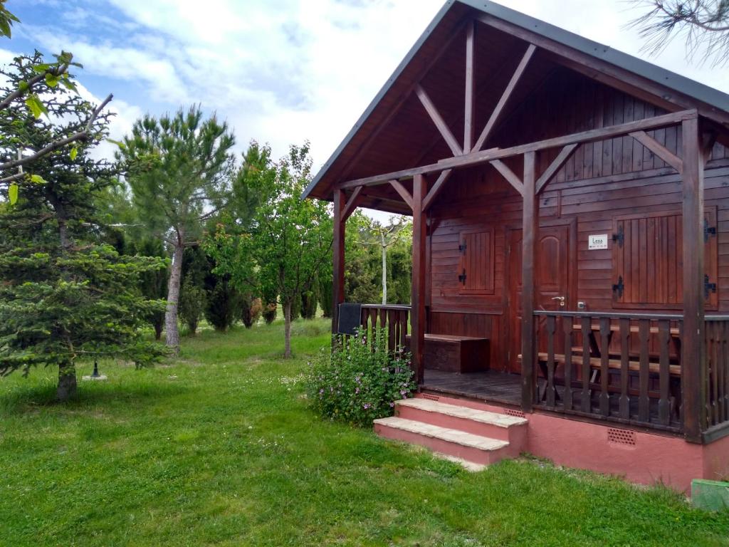 a small wooden cabin with a porch in a field at Cabañas de San Bartolomé in Villahermosa del Río