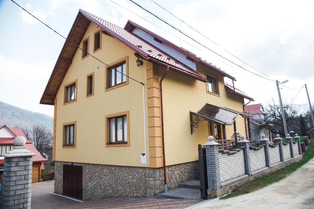 une petite maison jaune avec une clôture dans l'établissement Happy, à Yaremtche