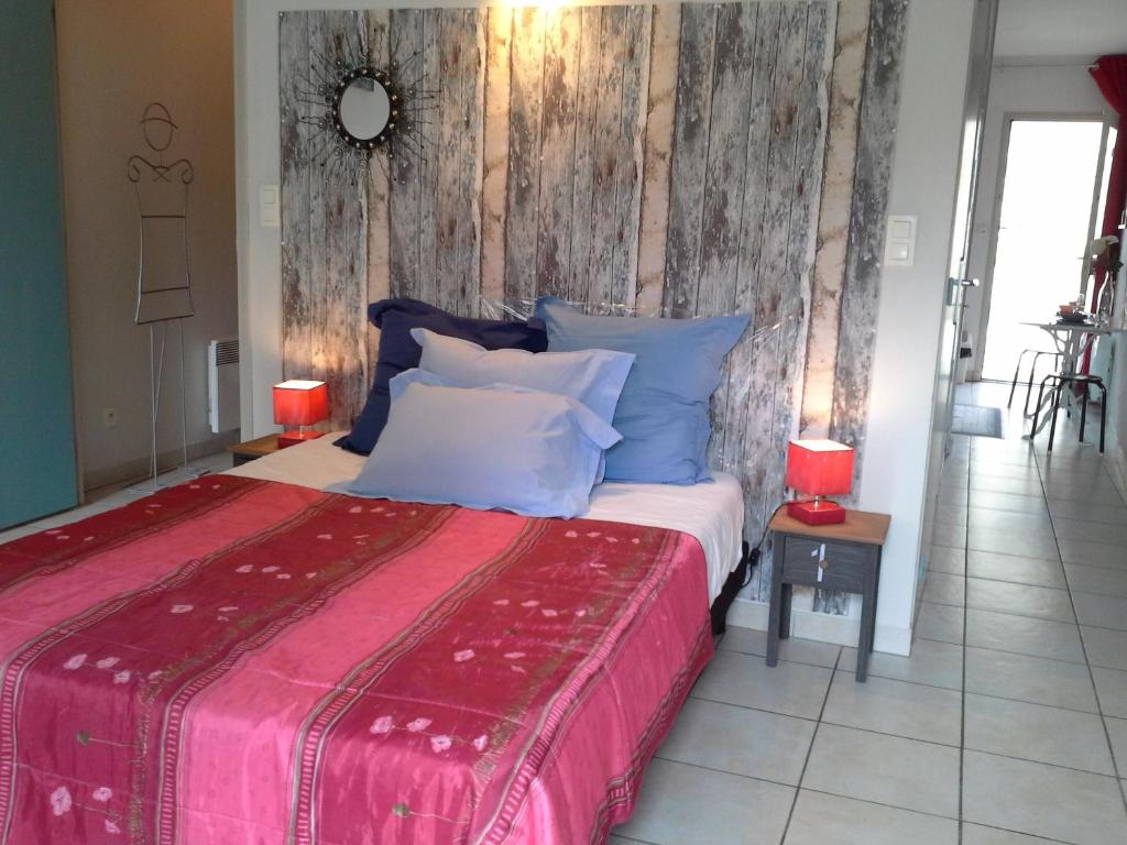 une chambre avec un grand lit avec une couverture rouge dans l'établissement Appartement Terrasse - Hypercentre, à Avignon