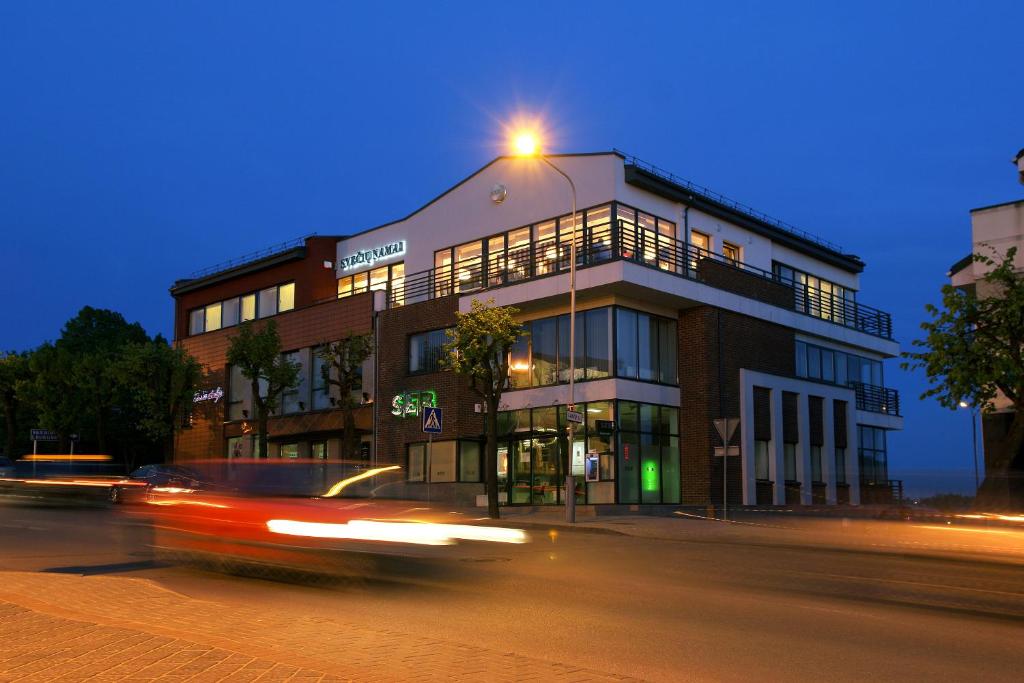 un coche pasando un edificio con una luz en la parte superior en Hotel Sinchronas, en Telšiai