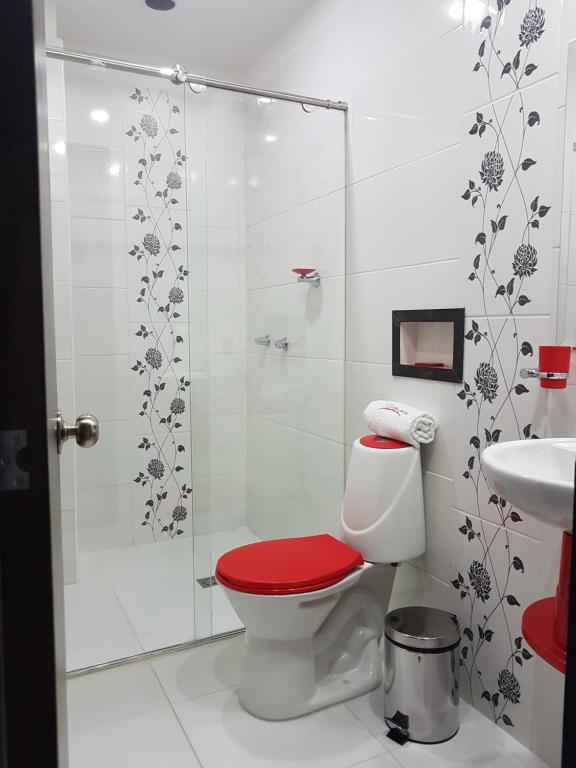 a bathroom with a shower and a toilet with a red seat at Hotel Orion in Chinchiná
