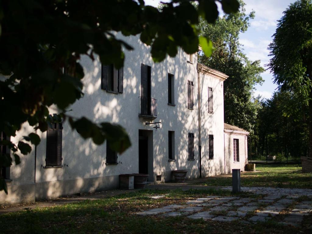 ein altes weißes Haus mit Bäumen im Vordergrund in der Unterkunft La Luna nel Pozzo in Parma