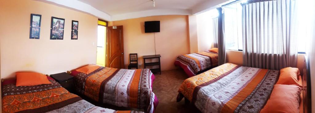 a hotel room with three beds and a television at Sami House in Cusco