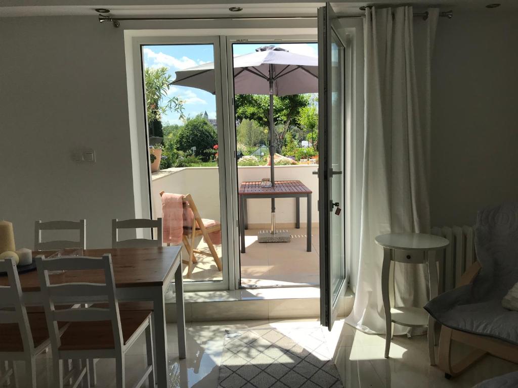 Otwarte drzwi na patio ze stołem i parasolem w obiekcie Apartament " POD NIEBIESKIM PAGAJEM " w mieście Mrągowo
