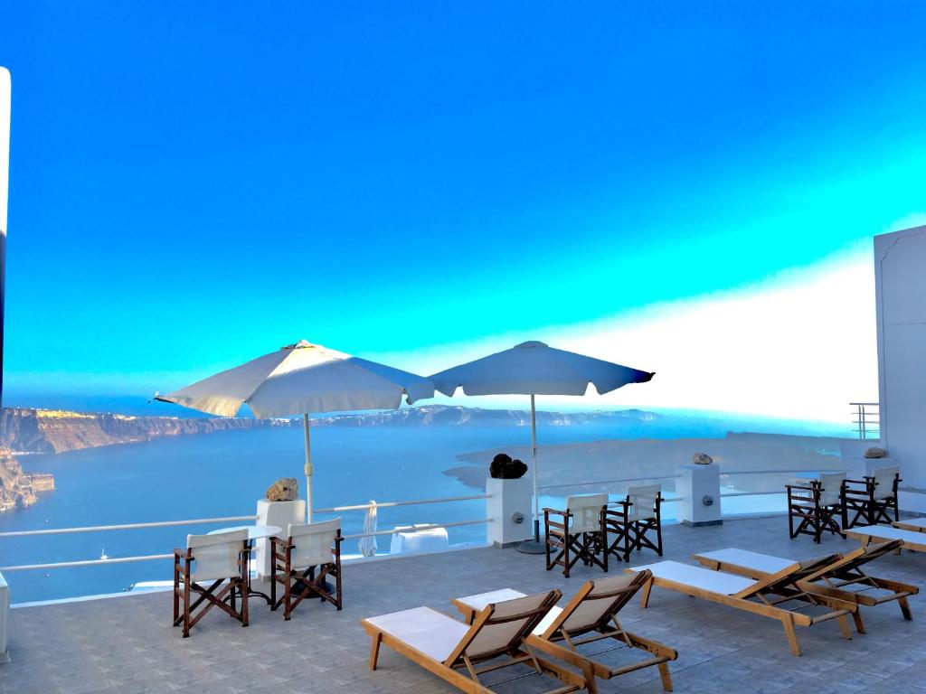 a patio with tables and chairs and a view of the water at Artemisia Apartment Caldera in Imerovigli