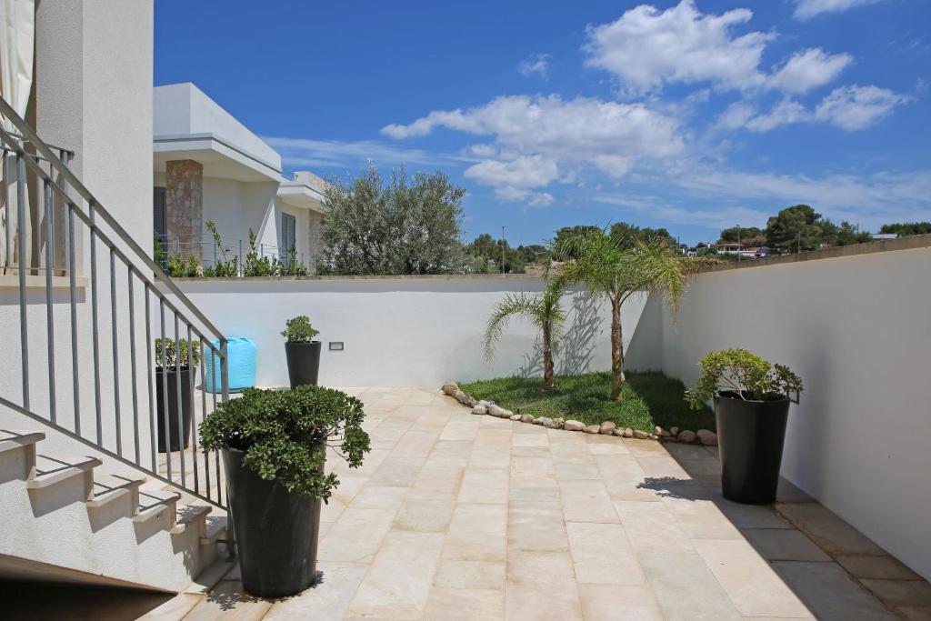 a patio with potted plants and a white wall at Villetta Sofia in Marina di Pescoluse