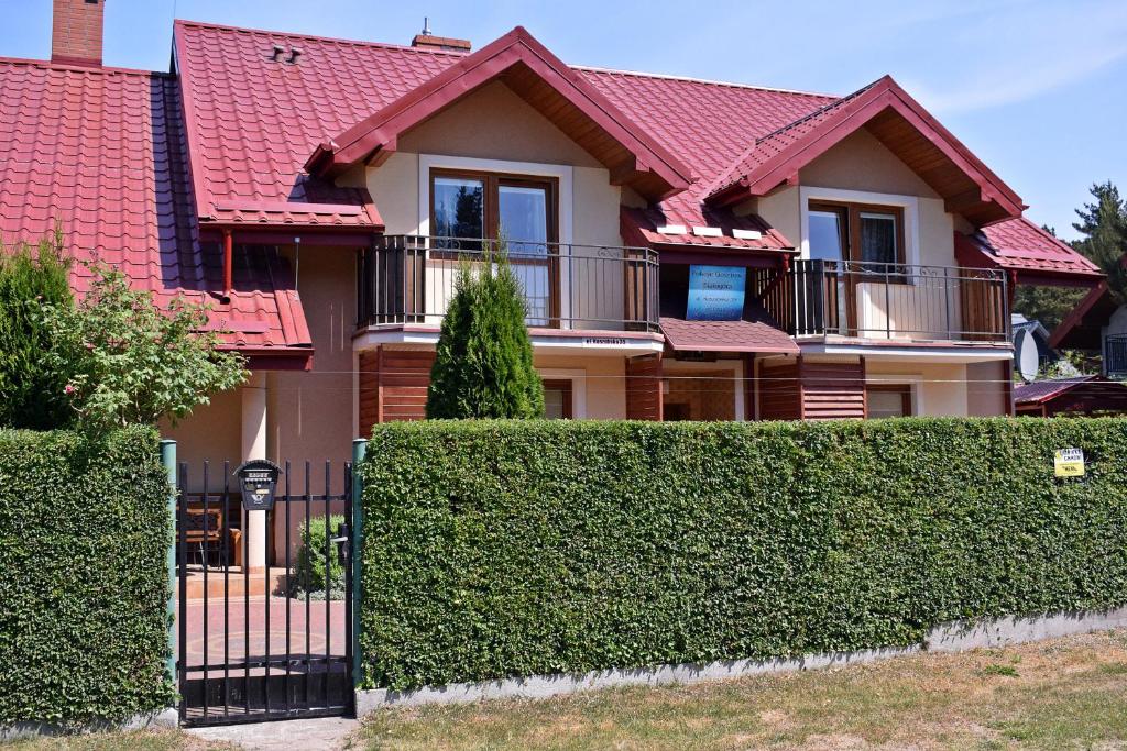 ビャウォグラにあるBiałogóra Pokojeの赤い屋根と柵のある家
