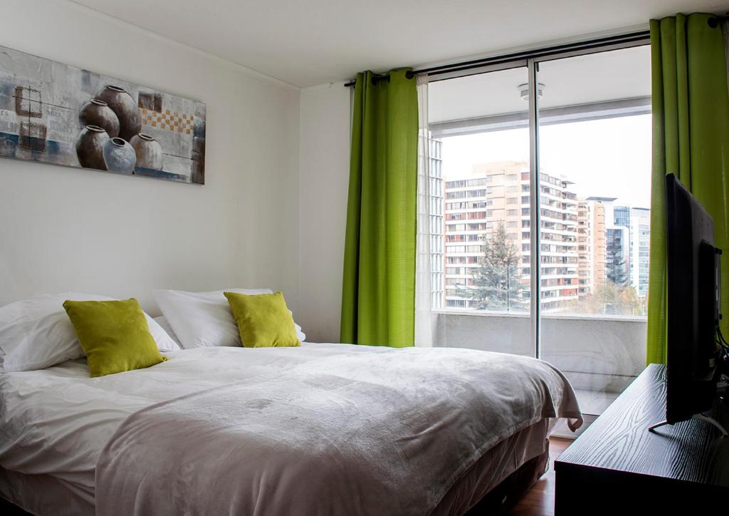 1 dormitorio con 1 cama con cortinas verdes y ventana en Kennedy Apartments Los Militares, en Santiago