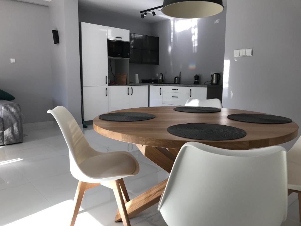 a kitchen with a wooden table and white chairs at Apartament El Sol in Łukęcin