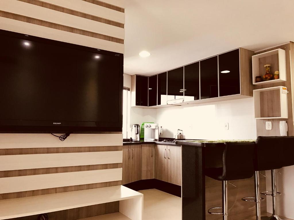 a kitchen with a large flat screen tv on the wall at Apartamento 401 Edificio London in Piratuba