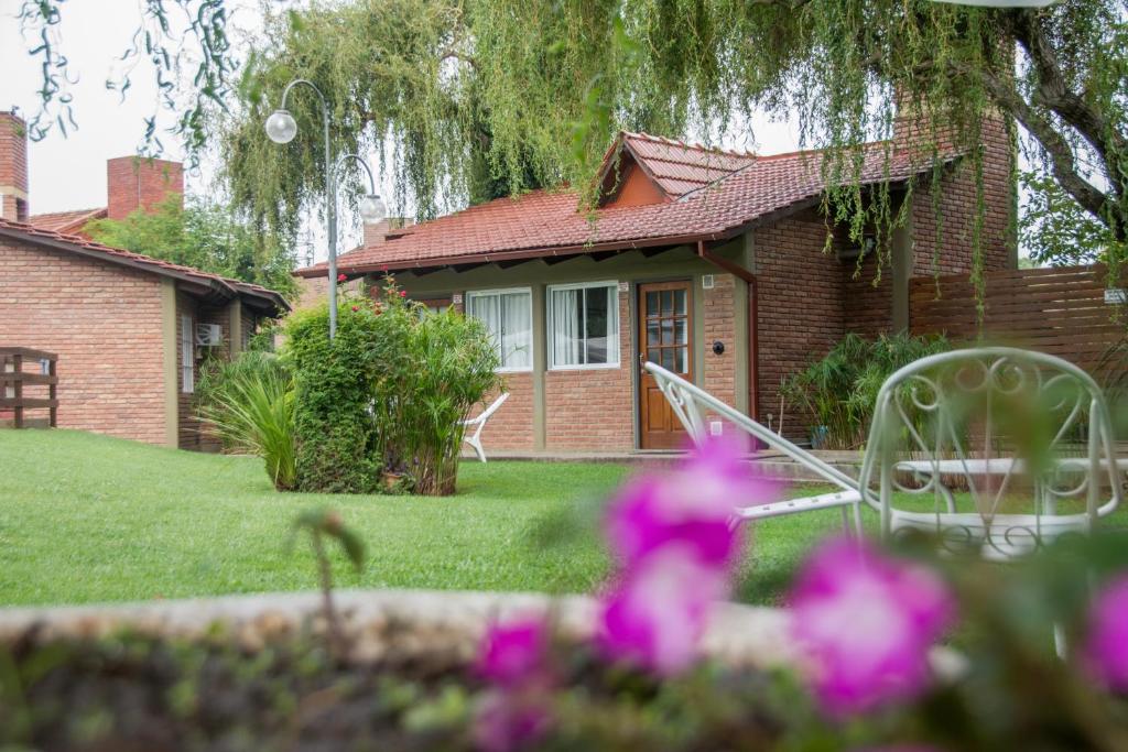 ein Haus mit einem Garten mit Stühlen und Blumen in der Unterkunft Tinajas del Lago Bungalows Apart in Villa Carlos Paz