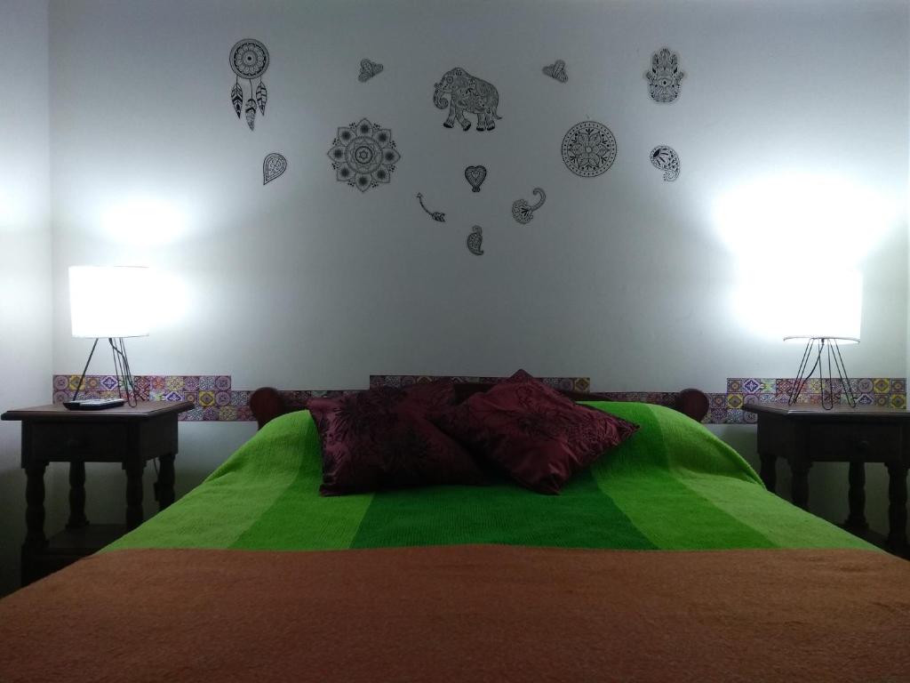 1 dormitorio con 1 cama verde con 2 mesas y 2 lámparas en Depto de Leo frente al mar en Mar del Plata