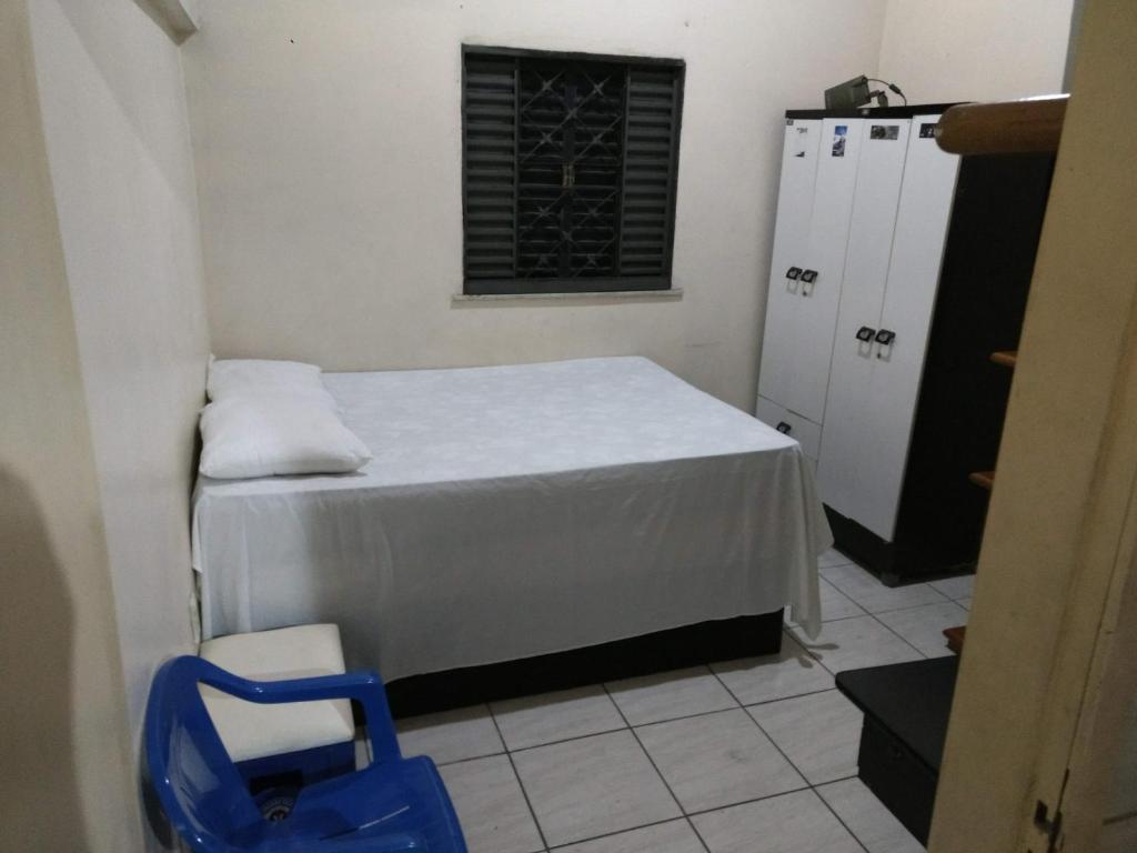 um pequeno quarto com uma cama e uma cadeira azul em Casa em Fortaleza