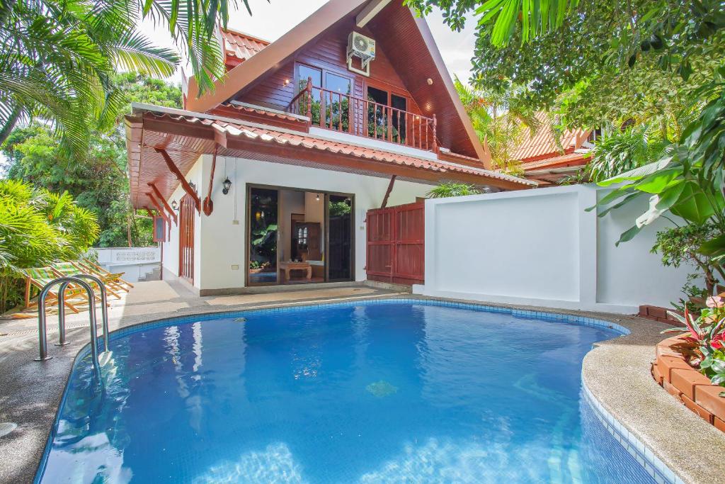 a swimming pool in front of a house at Traditional Thai Villa in Tropical Nature, 4BR & Pool, near Rawai Beach in Nai Harn Beach