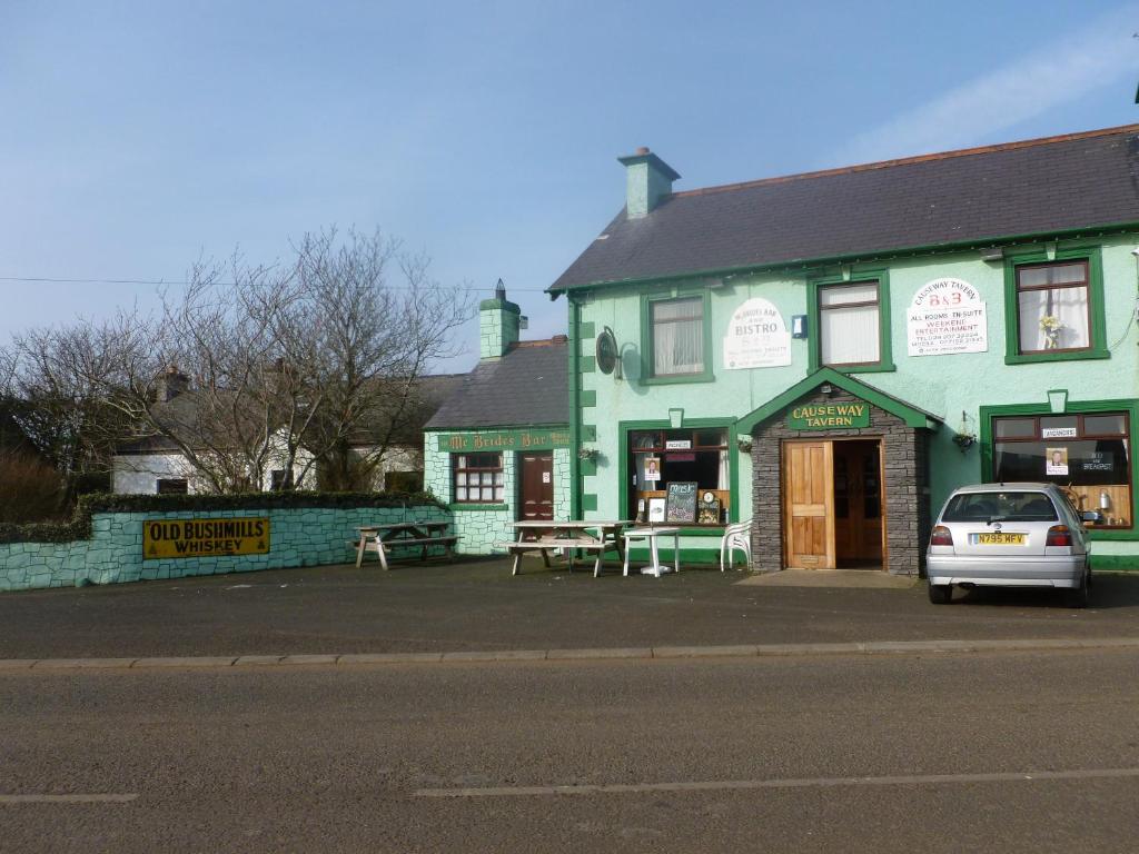 a green building with a car parked in front of it at Causeway tavern bed & breakfast in Bushmills