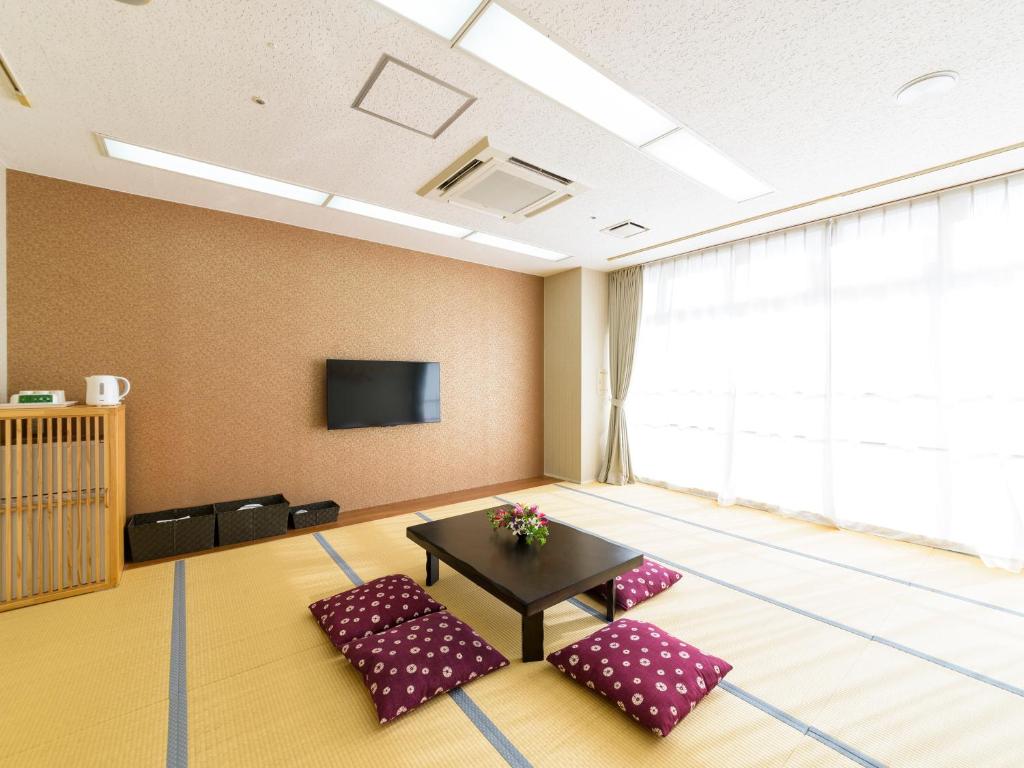 a room with two chairs and a table and a tv at Hotel Abest Naha Kokusaidori in Naha